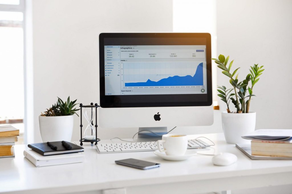 Clean office desk setup with an iMac displaying an analytics dashboard